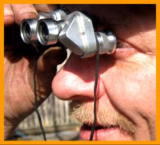 Man Looking Through Miniature Binoculars