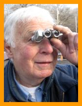 White haired man looking through binoculars