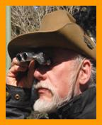 Bearded man in Australian hat looking through binoculars