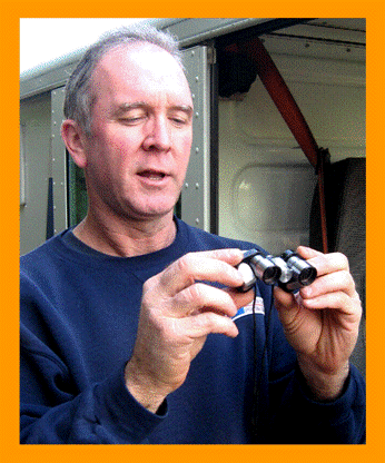Postman Examining Miniature Binoculars