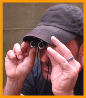 Man Peering through Miniature Binoculars 