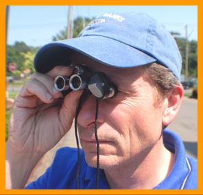 man looking through miniature binocularsy