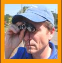 man looking through miniature binocularsy