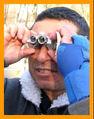 Disabled man using miniature binoculars.