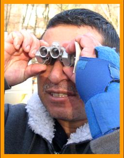 Disabled man using miniature binoculars.