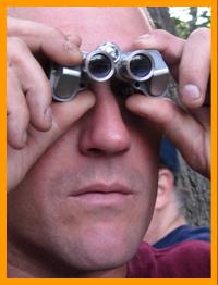 Man looking through miniature binoculars. www.miniaturebinoculars.com