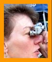 woman looking through miniature binoculars. www.miniaturebinoculars.com