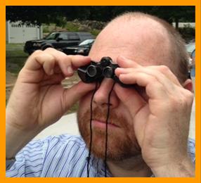 Man Looking Through Tiny Binoculars