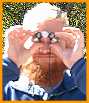 man looking through miniature binoculars