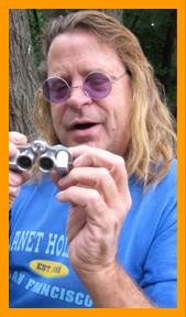 Long Haired Man Examing Small Binoculars