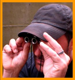 Man Peering through Miniature Binoculars.
Man looking through binoculars.
Man using binoculars.
Homme observant avec des jumelles miniature.
Man beobachtet mit einem miniatur fernglas.
Homme observant avec des jumelles miniature.
Man Observerar med miniatur kikare.
L'uomo osserva col il binocolo in miniatura. 
Man met verrekijker.
Man med kikkert.
Mezczyzna z lornettka.
Muz s dalekohled.
Mand med likkert.
Tavcsovel rendelkezo ferfi.
Mies jolla on kiikarit.
Homem com binoculos.
Virietis ar binokli.
Vyras so ziuronu.
6x15 binoculars.